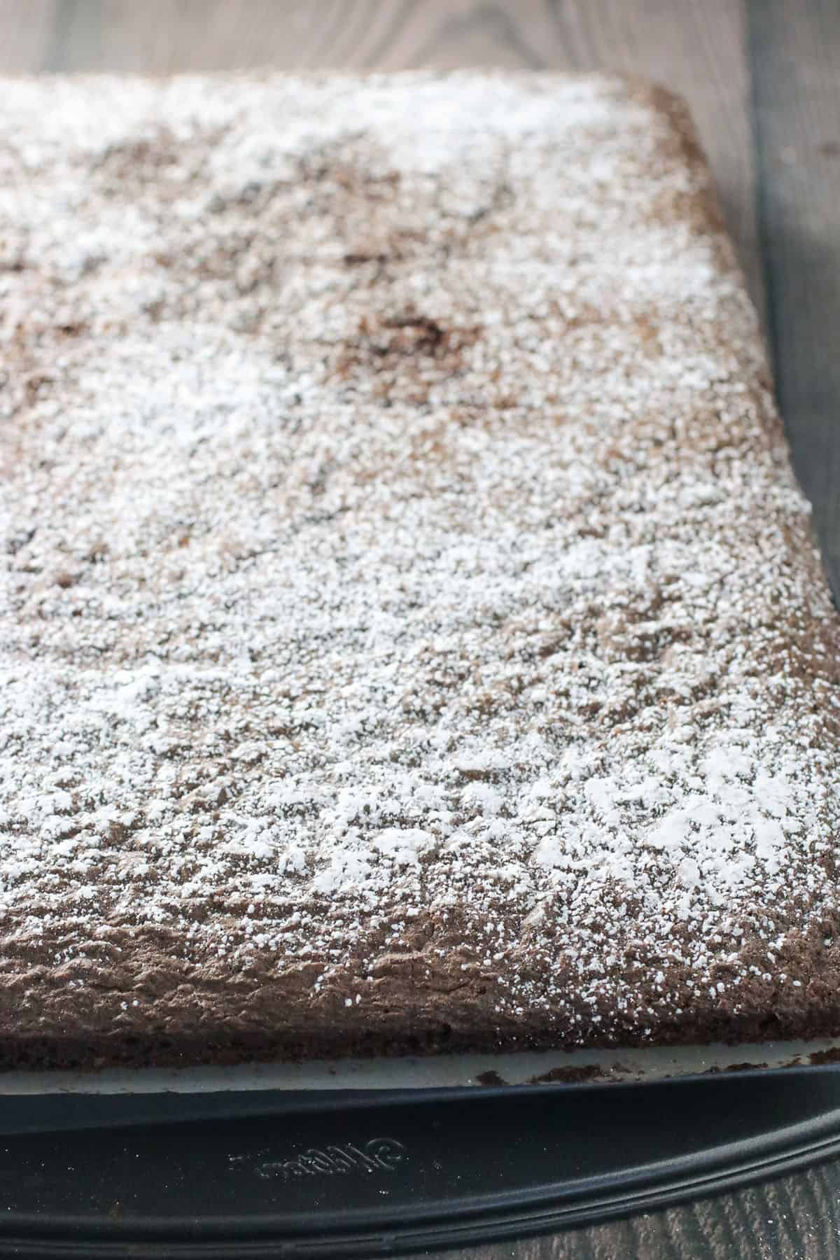 The cake on its right side up with powdered sugar on top. It is now ready for rolling.