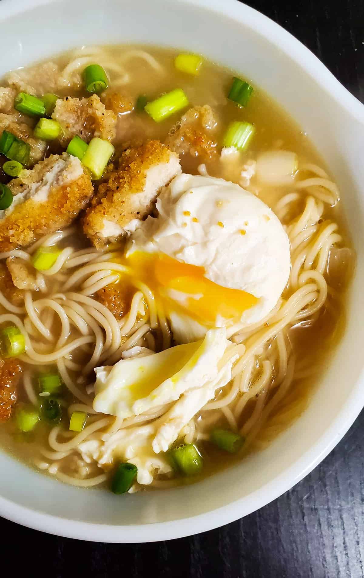 Egg Ramen in a bowl, topped with chicken strips and poached egg.