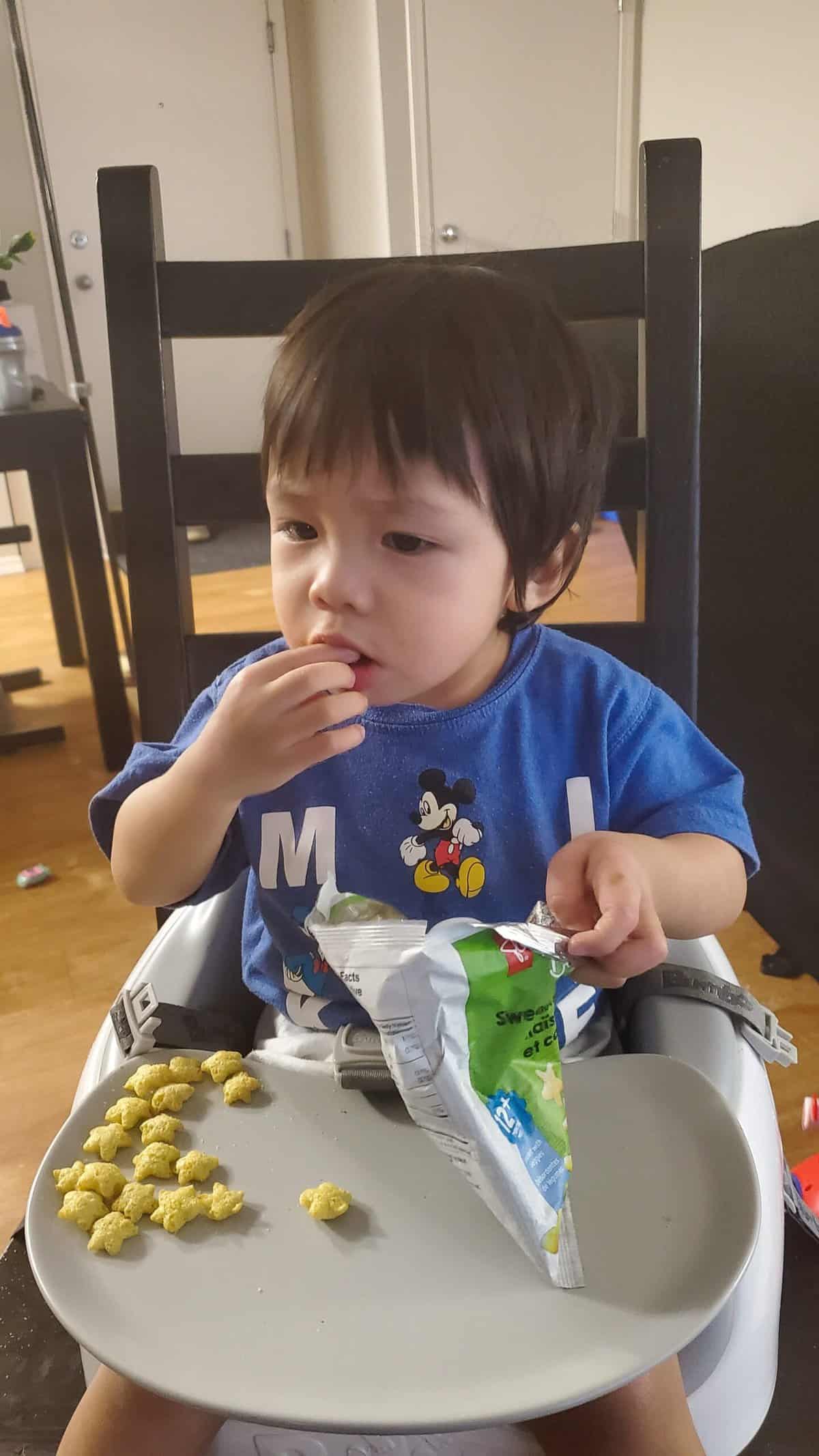Baby boy eating snack.