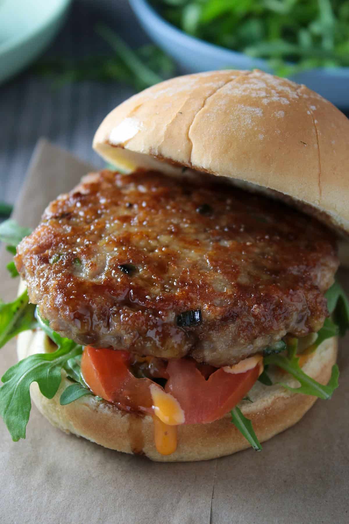 An Asian chicken burger with the top bun lifted off to show the chicken patty.