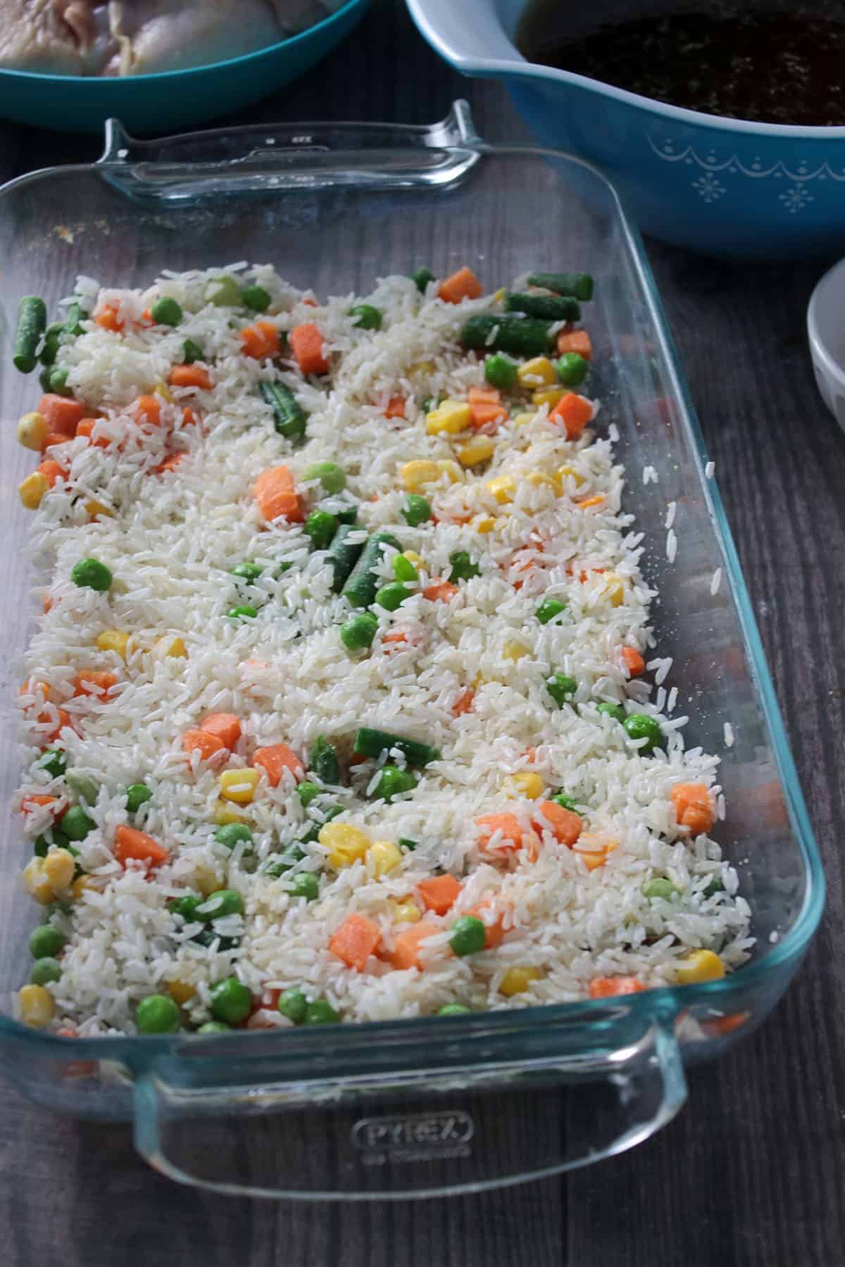 A mixture of rice and mixed veggies on a baking dish.