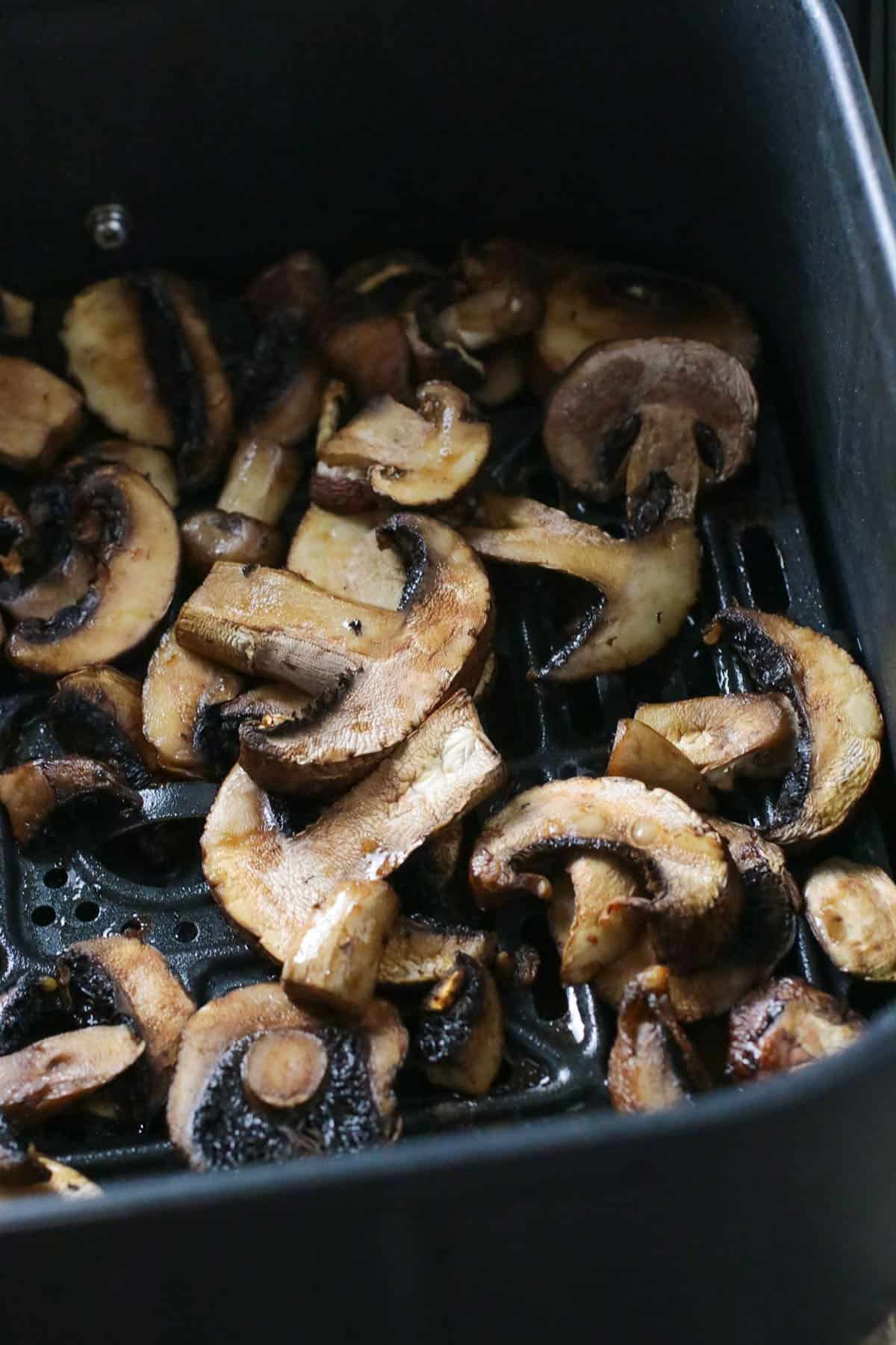 Cooked mushrooms on an air fryer basket.