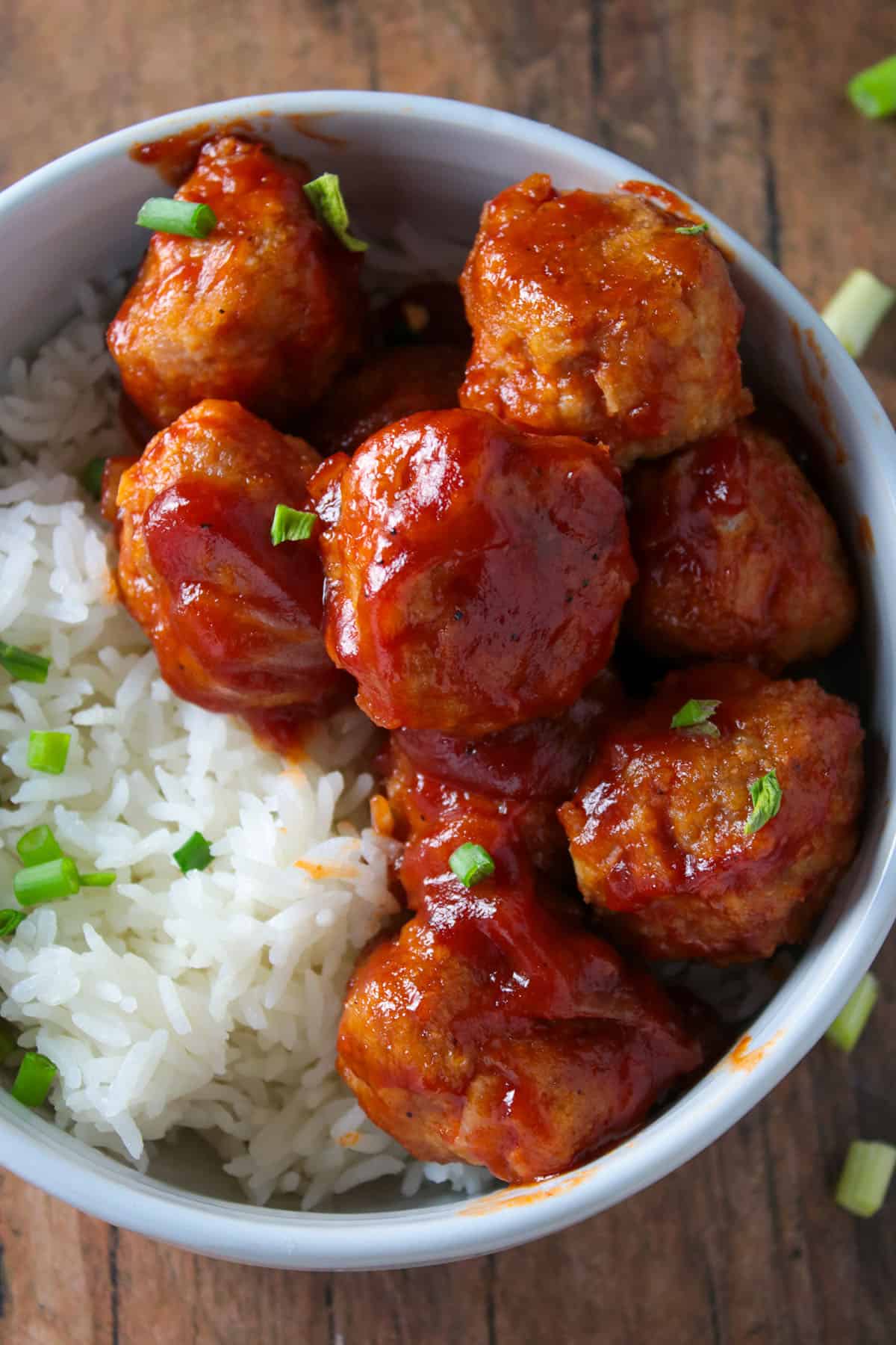 Top angle shot of baked chicken meatballs in a bowl with rice.