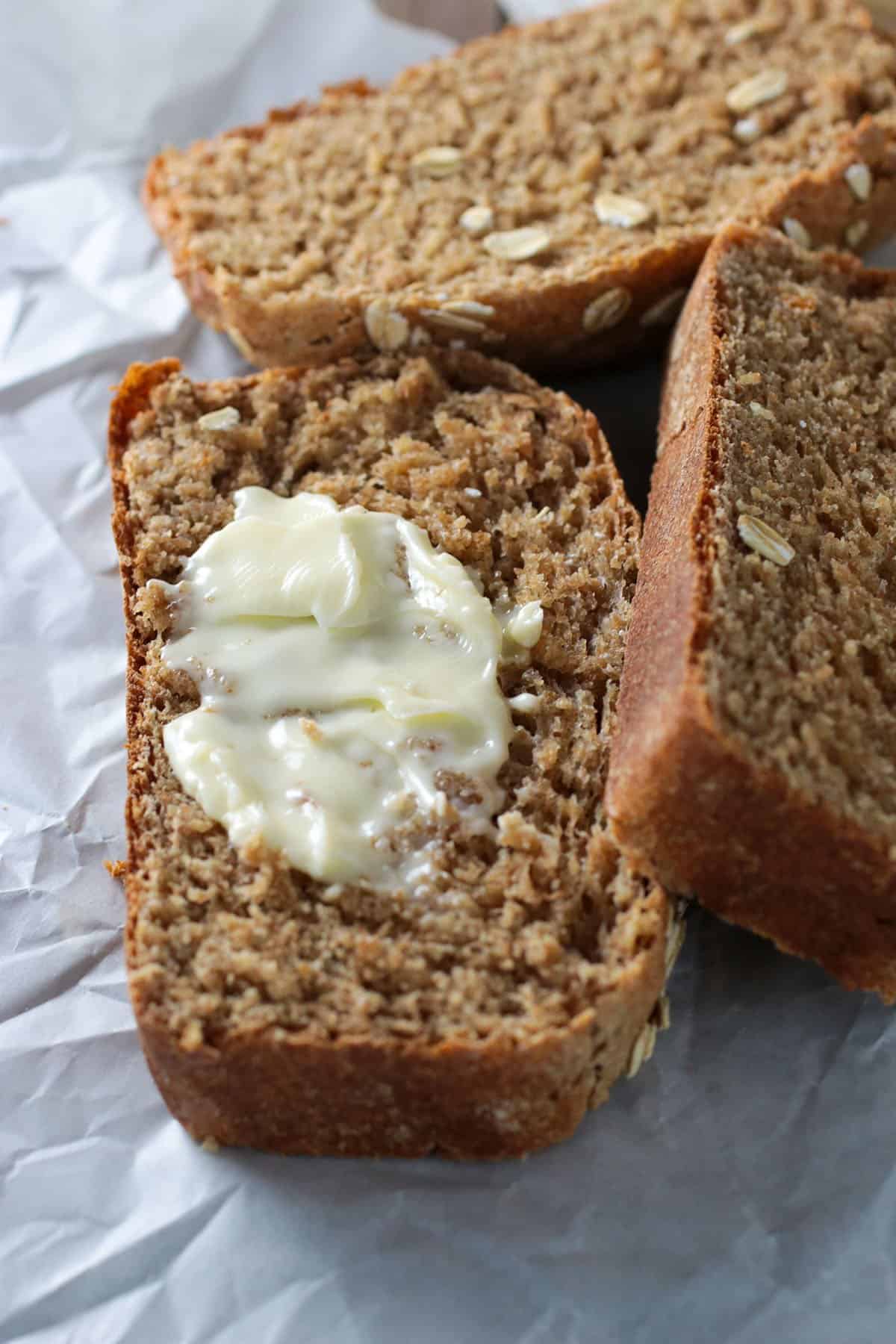 A slice of Spelt Oatmeal bread with a pat of butter.