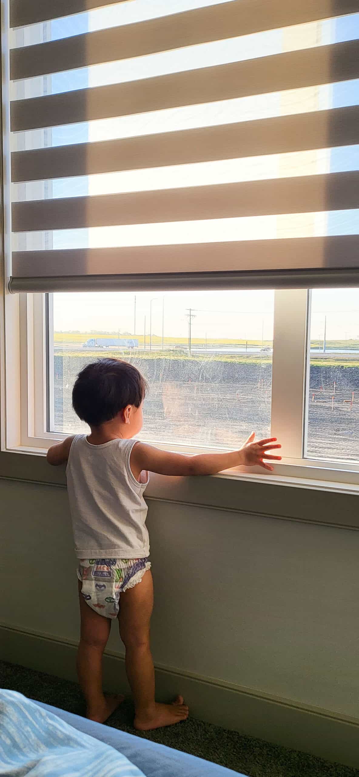 Little boy looking through a window.