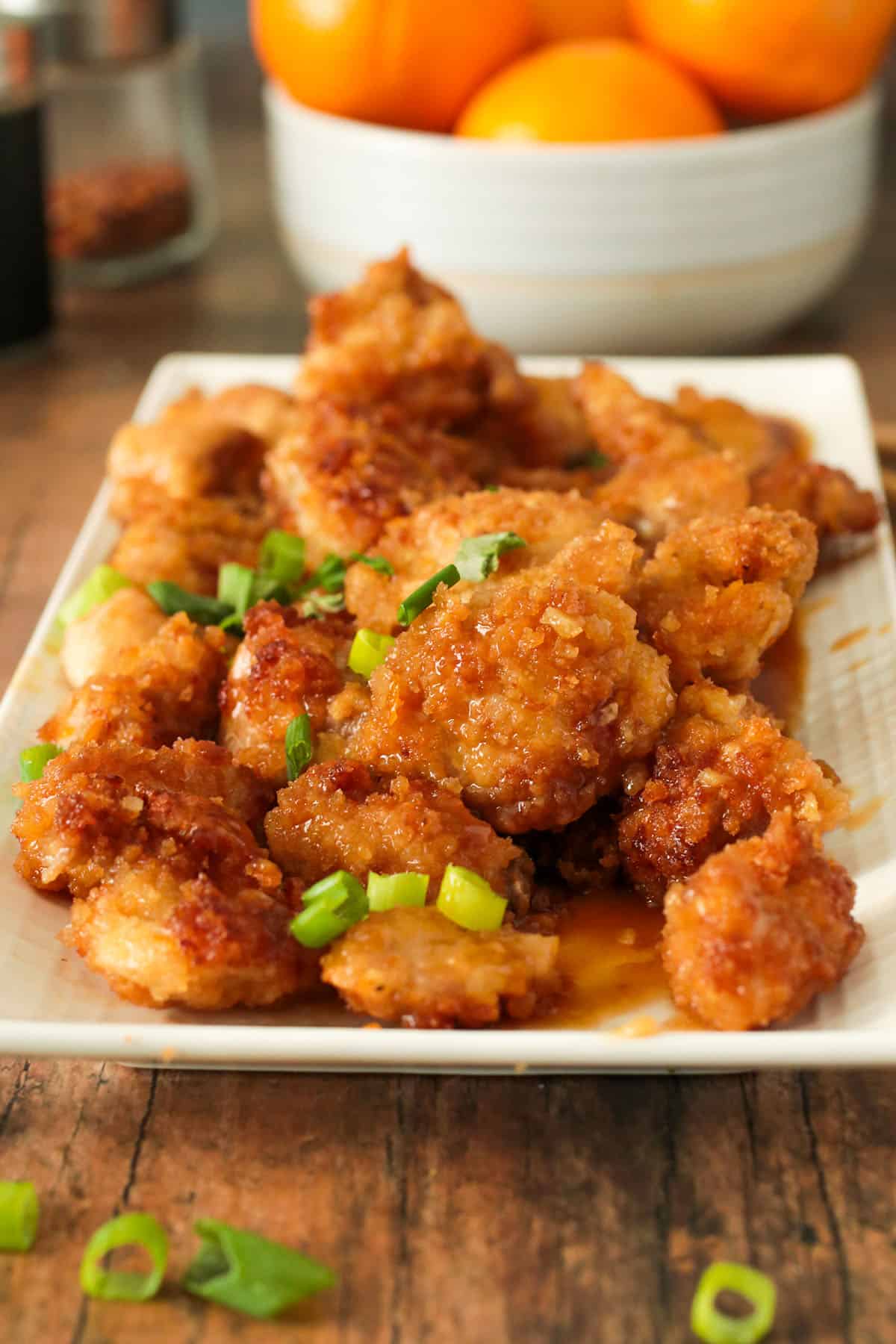 The orange chicken served in a platter and garnished with green onions.
