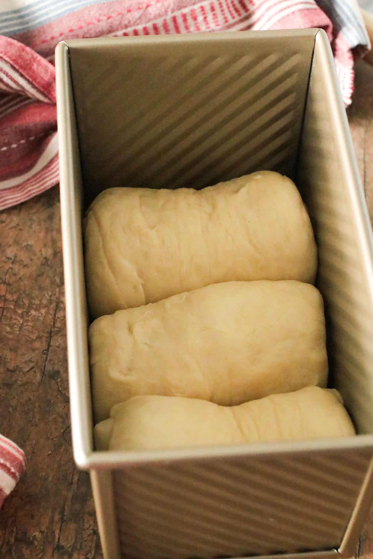 The logs of dough arranged in a Pullman loaf.