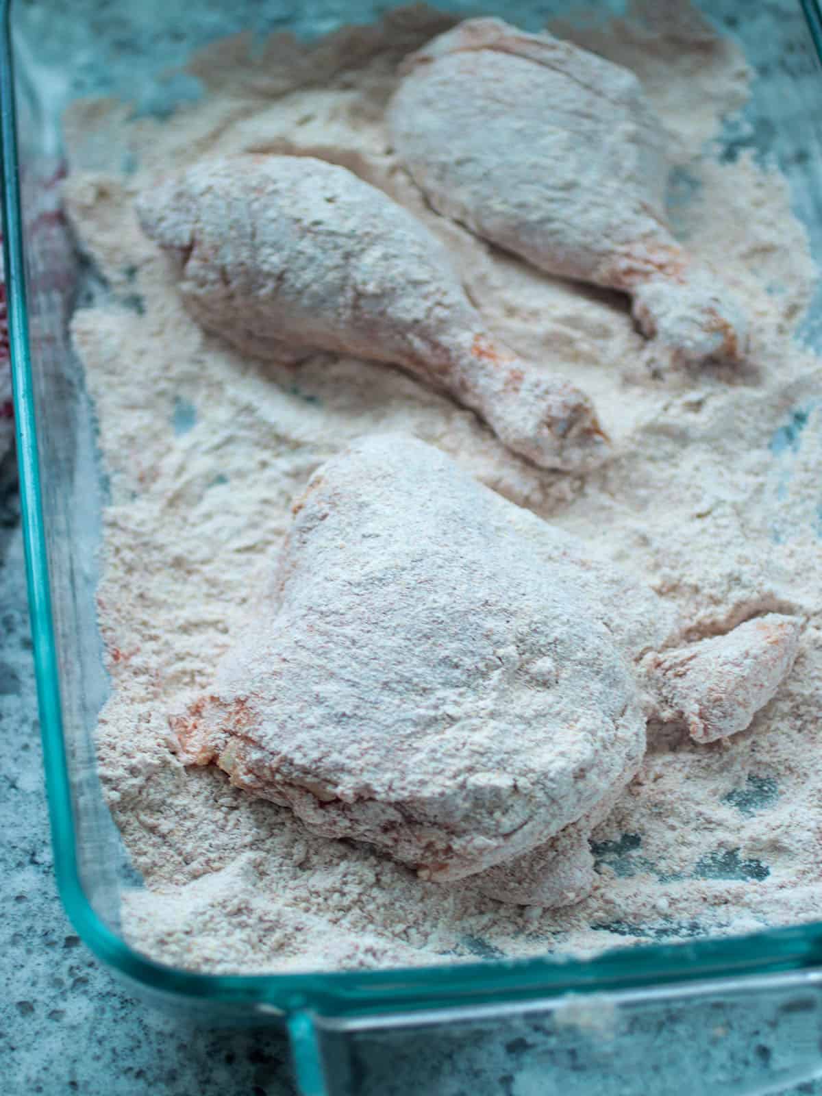 Coating the chicken with the flour seasoning mix.