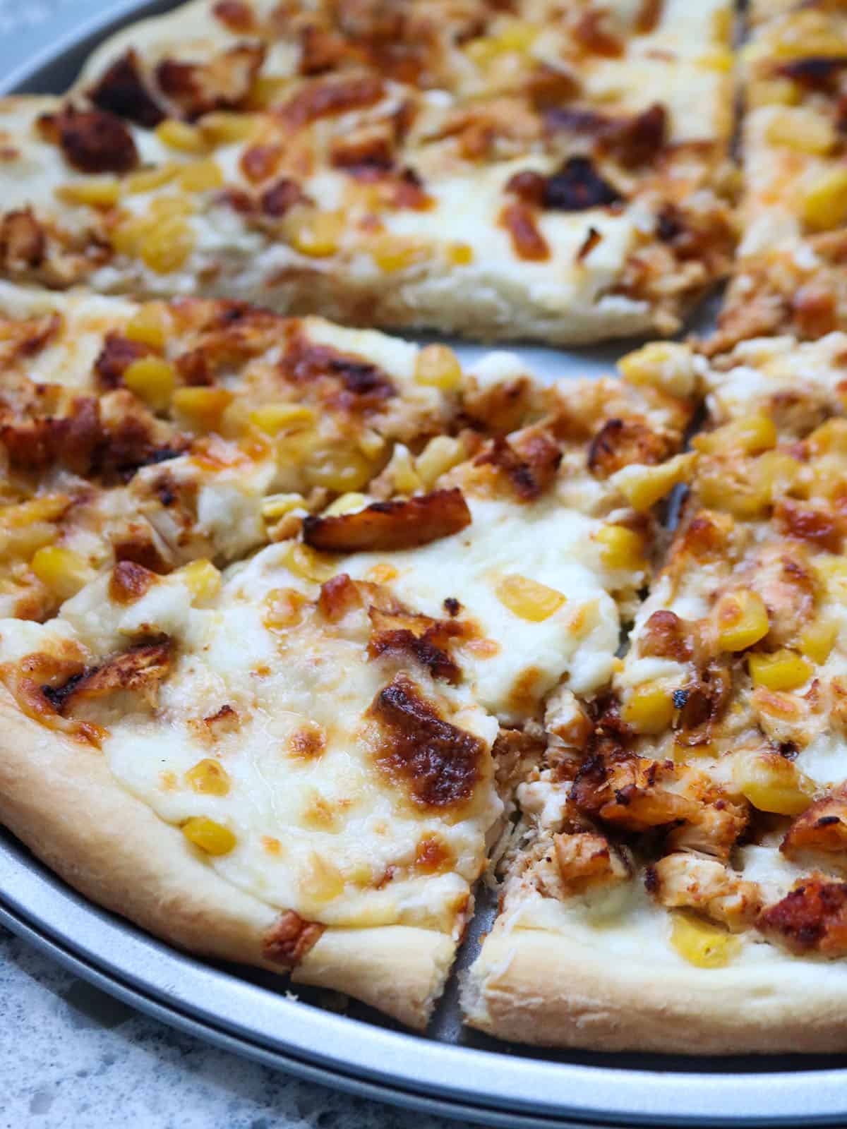 Close up shot of cajun chicken and corn pizza.