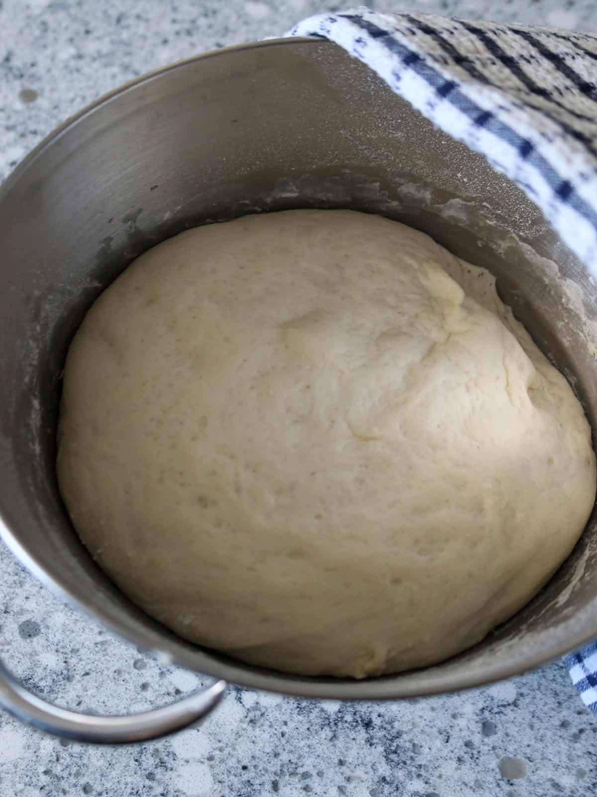 The pizza dough risen in the bowl.