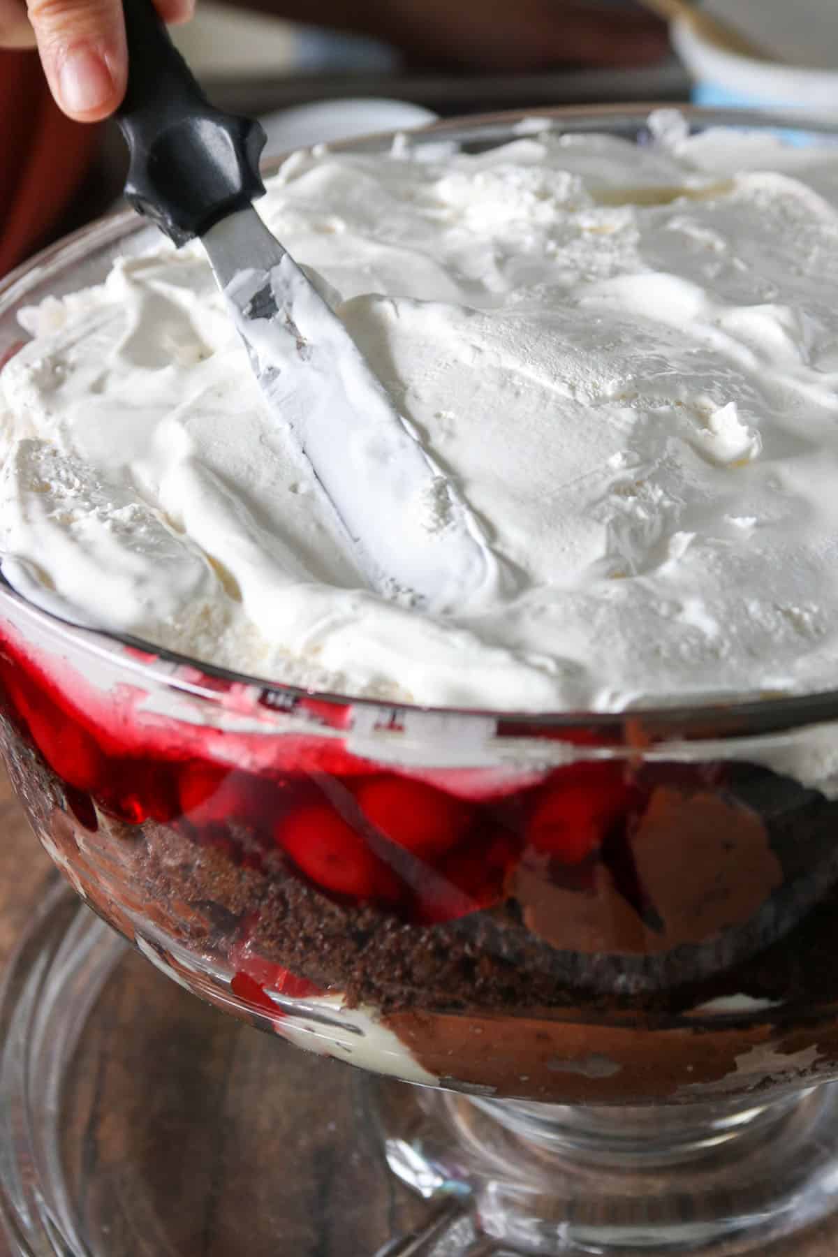 Spreading the cool whip topping on the trifle.