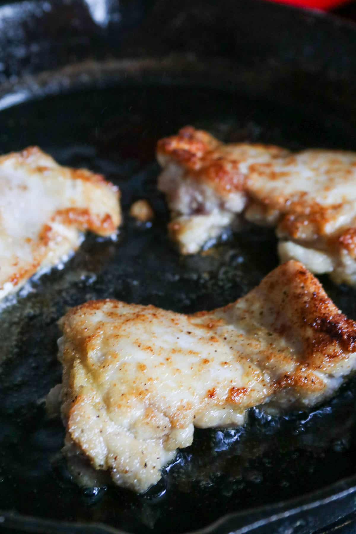 Cooking chicken thighs in a skillet.