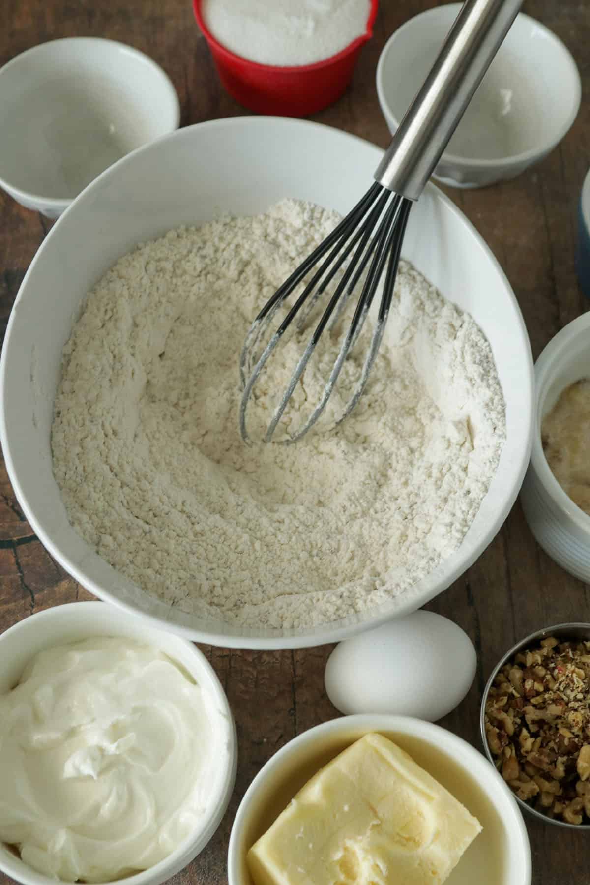 All the powder ingredients for the banana cake whisked together in a bowl. The  remaining ingredients surrounding it.