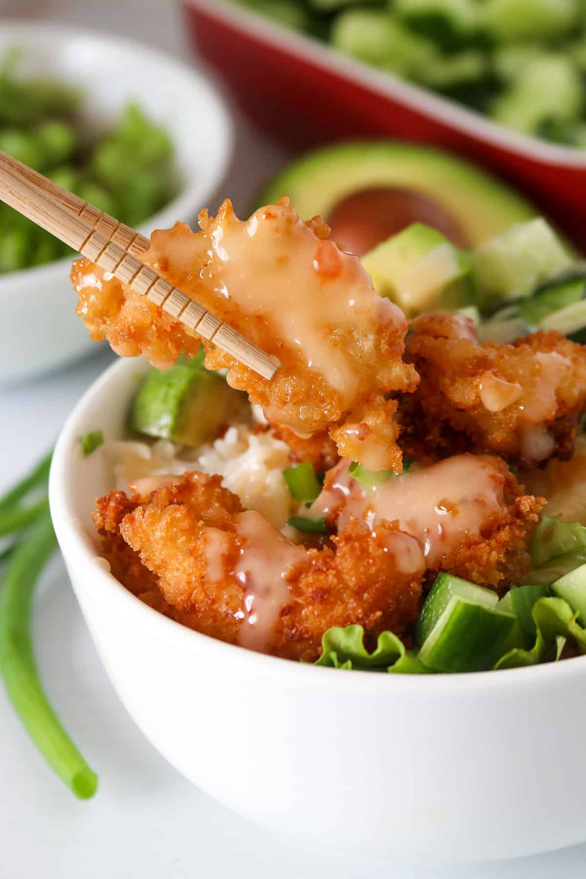 Bang bang shrimp rice bowls photo. A shrimp on a chop stick