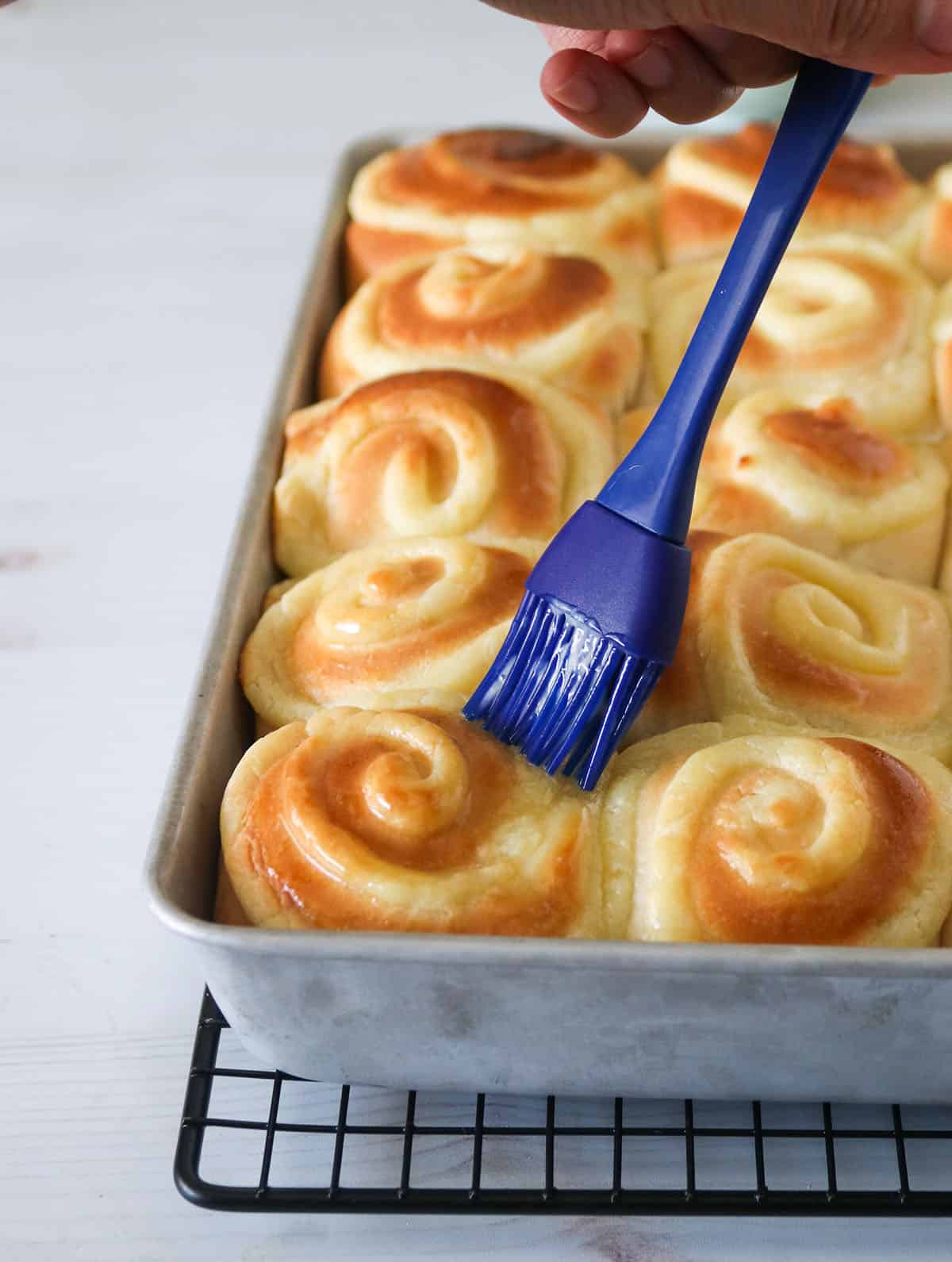 Brushing melted butter on the baked buns.