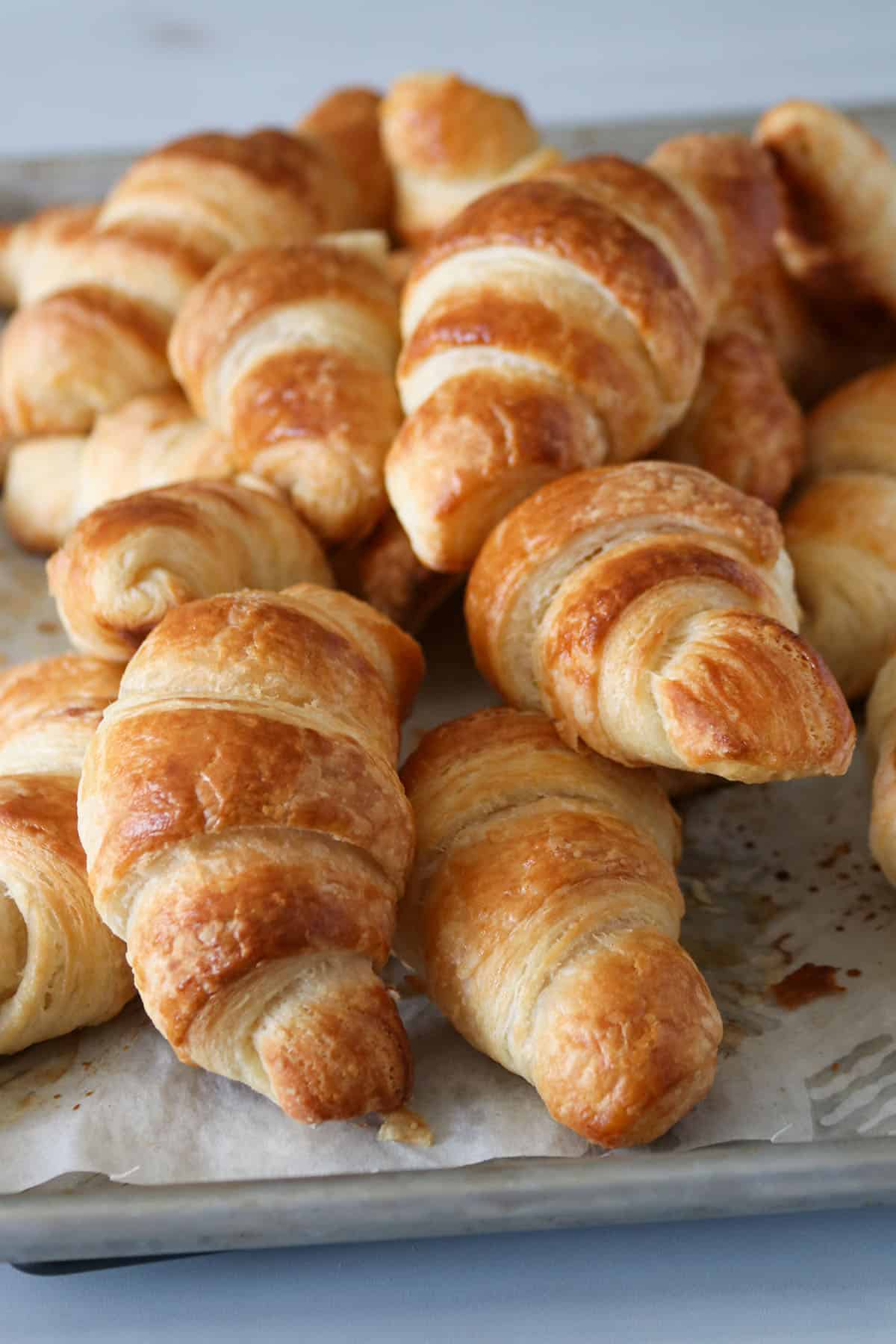 Croissants piled on a baking pan.