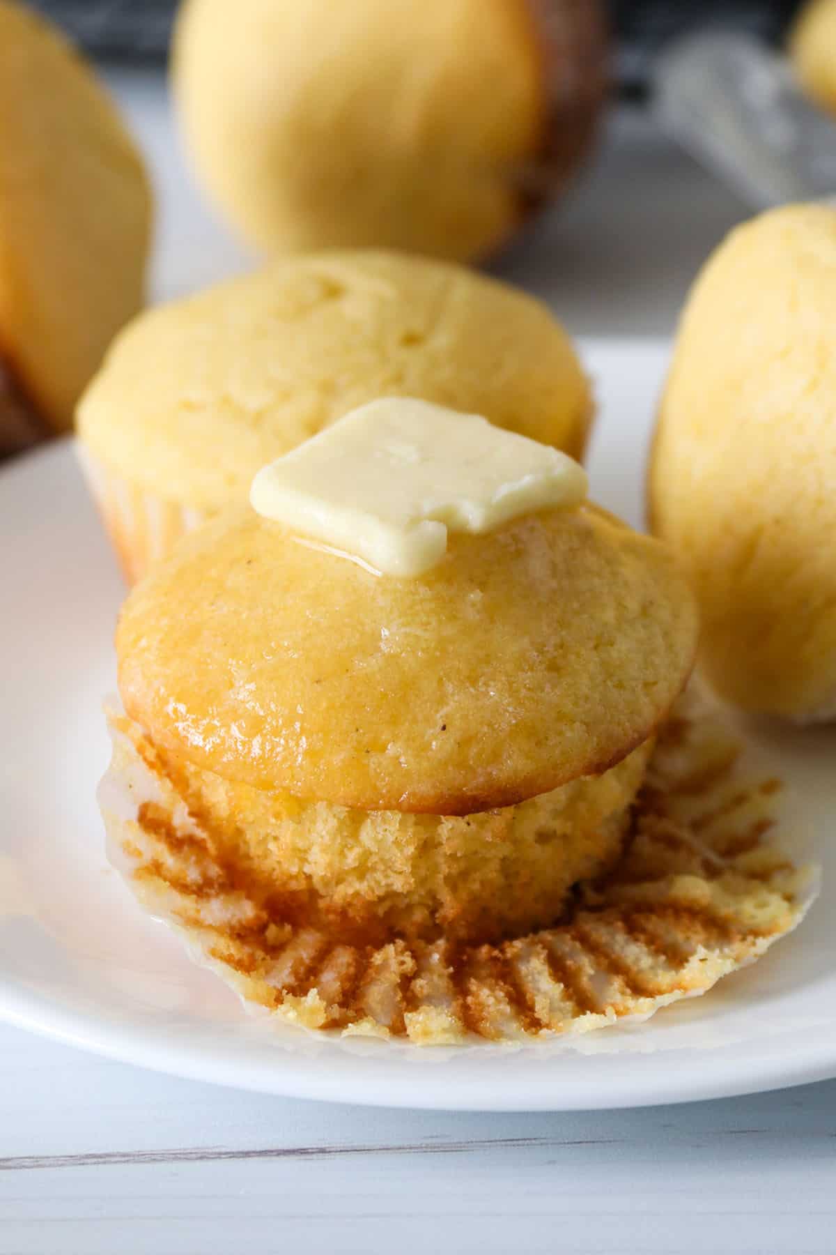 A cornbread muffin topped with butter.