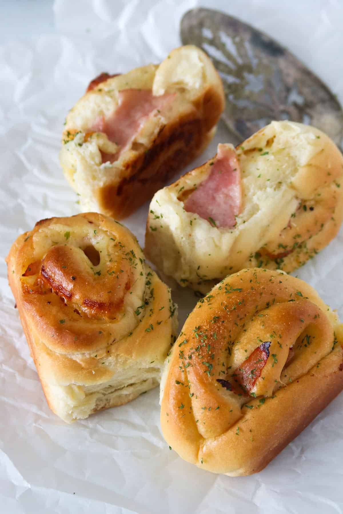 Pieces of ham and cheese rolls on a white paper.
