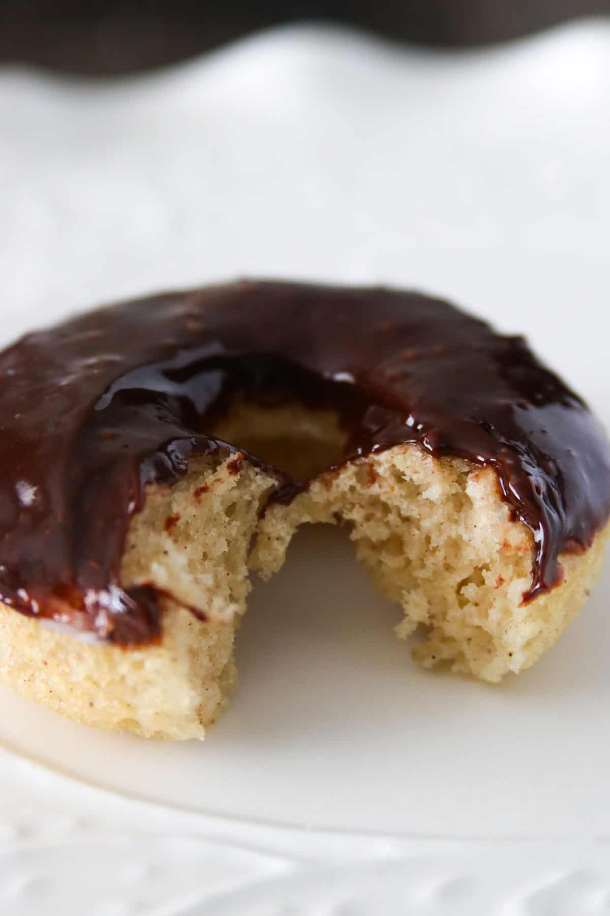 A chocolate donut with a bite, showing the crumbs.