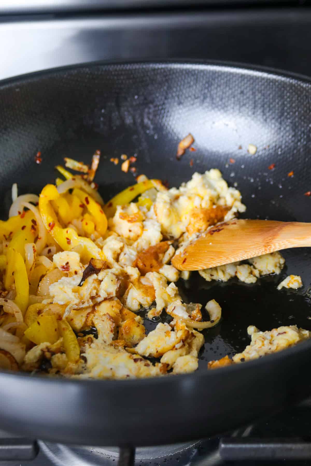 Breaking the eggs apart into bite size pieces in  the wok. 