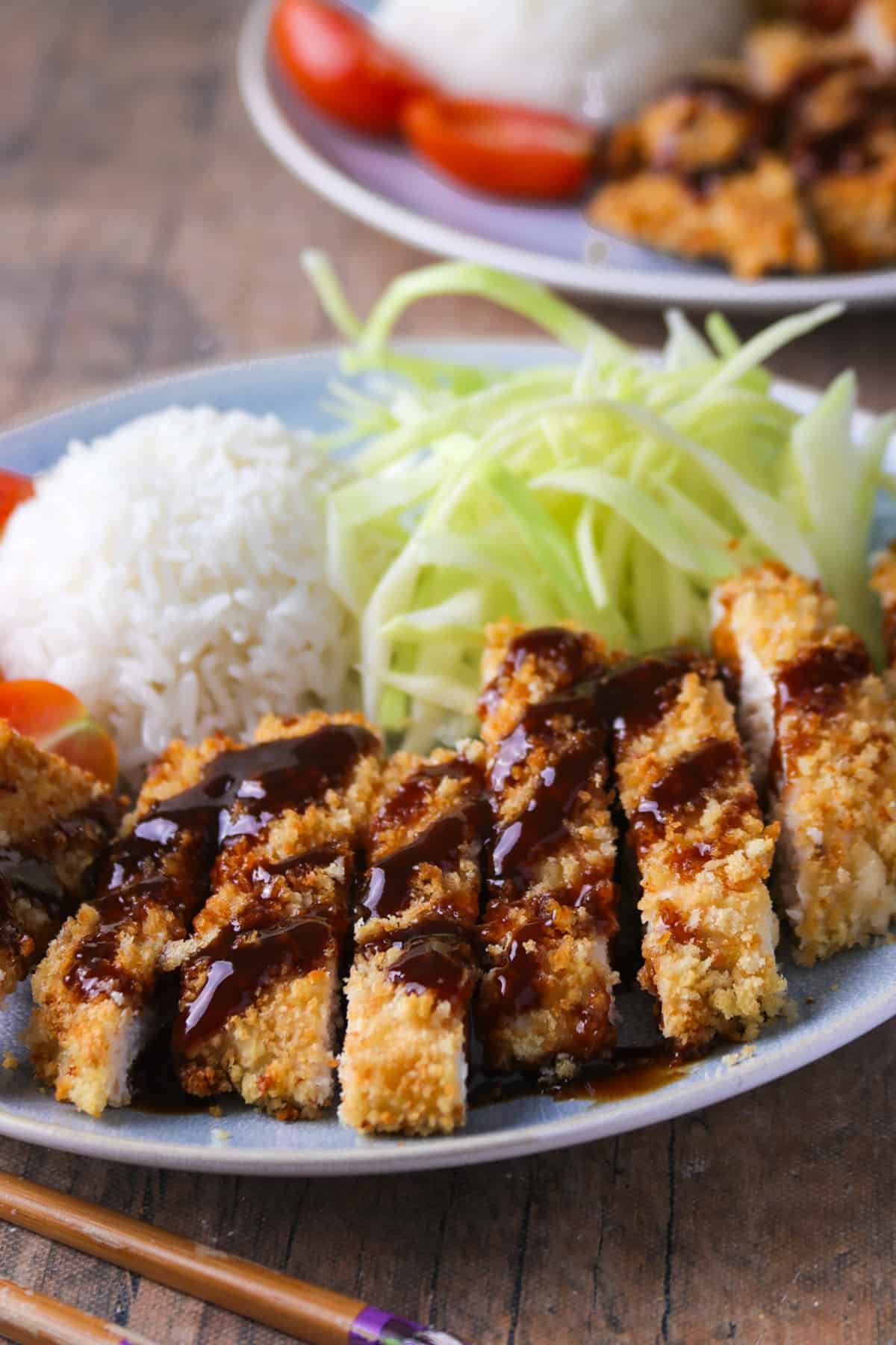 Sliced chicken katsu on a plate, served with rice and cabbage,
