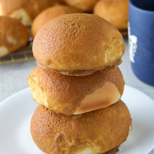 3 coffee buns stacked on a white plate.