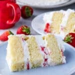 A slice of strawberry short cake layer cake on a plate.